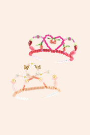 Set of colorful tiaras with decorative elements on a light pink background