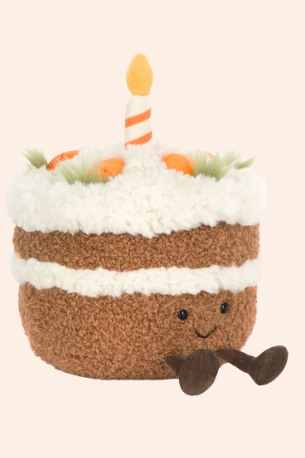 Plush toy shaped like a birthday cake with a candle on a beige background