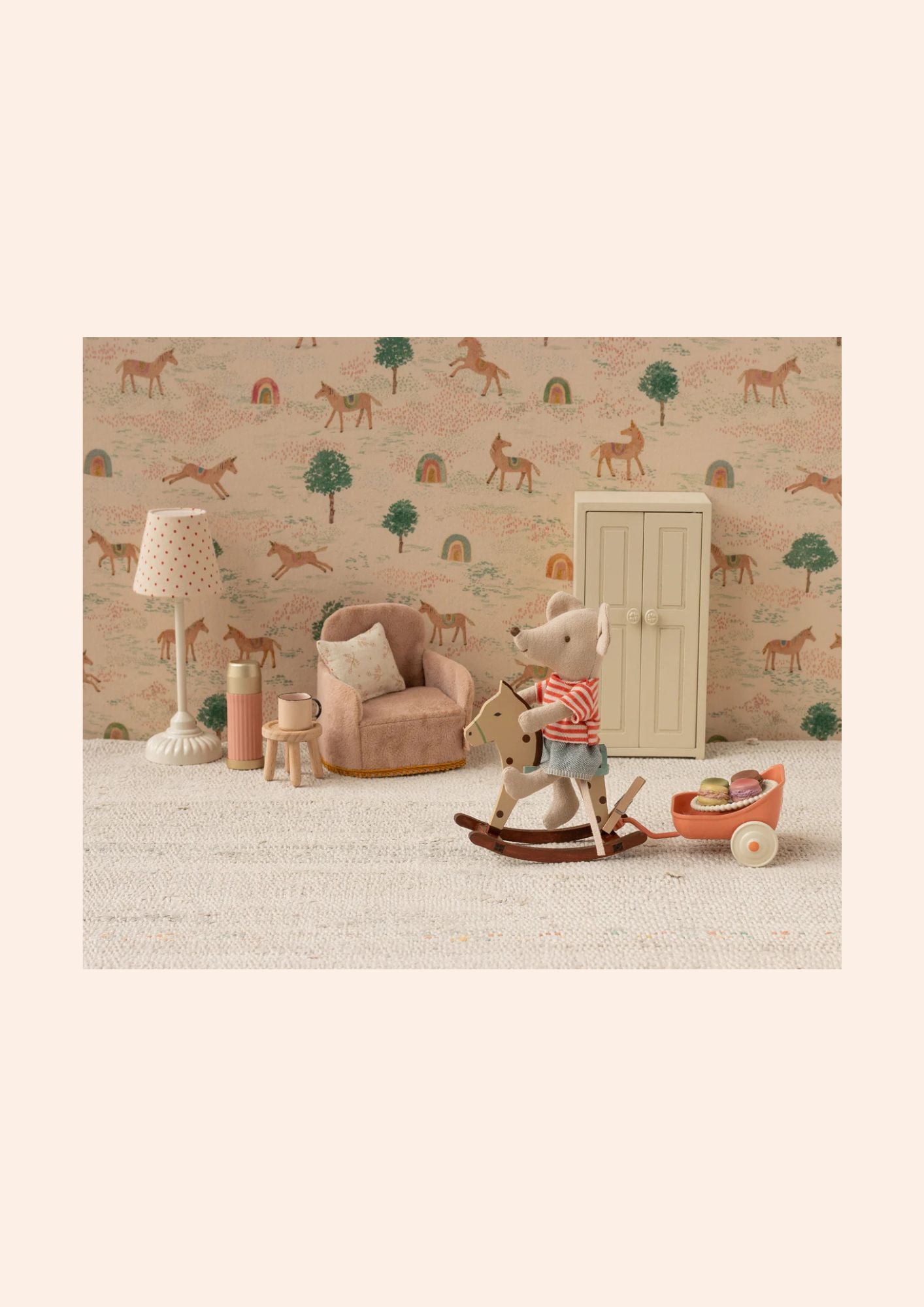 Children's room with teddy bear, rocking horse, and toys against a wallpapered wall.
