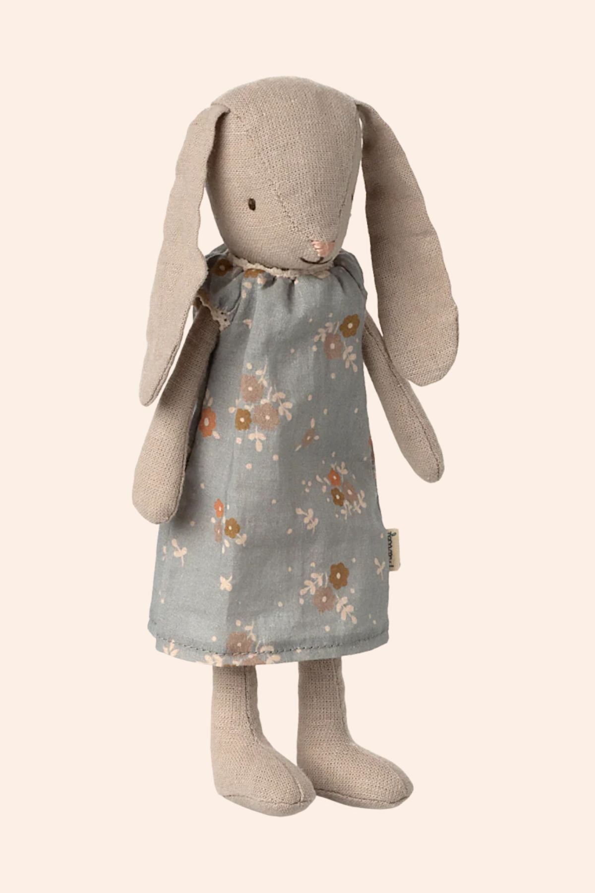 Stuffed bunny toy wearing a floral dress on a beige background