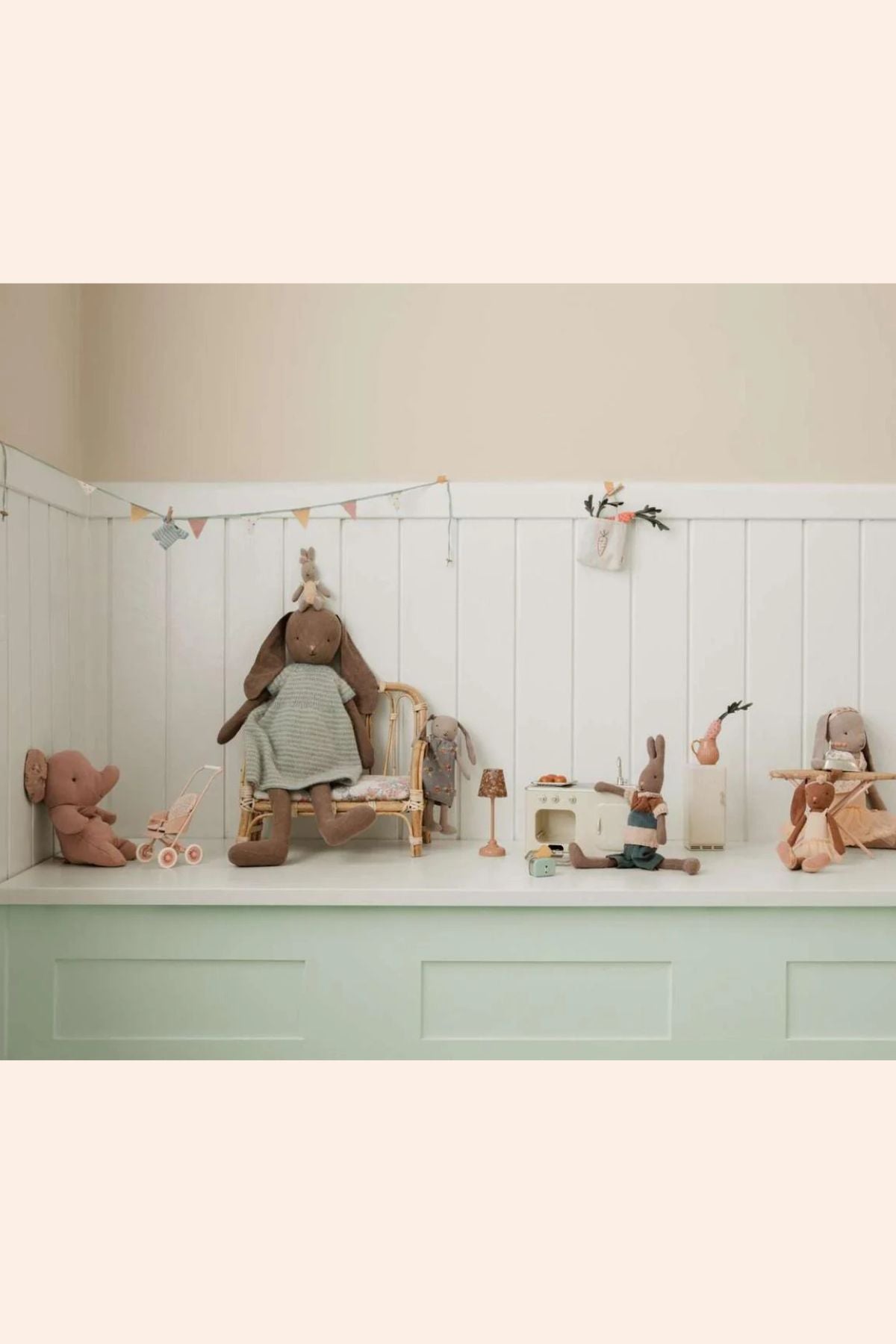 Children's toys and furniture arranged on a light green shelf against a white paneled wall.