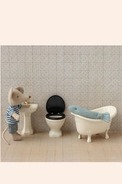 Small mouse-like creature in a bathroom setting with a sink, toilet, and bathtub.