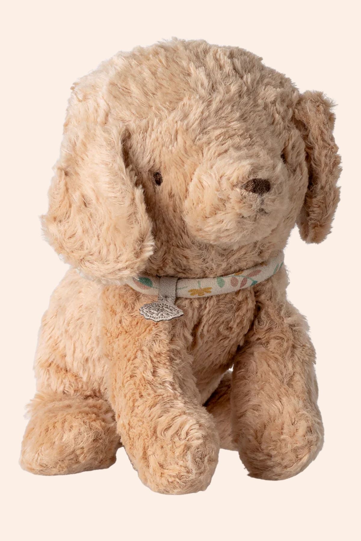 Beige stuffed dog toy with a collar on a beige background