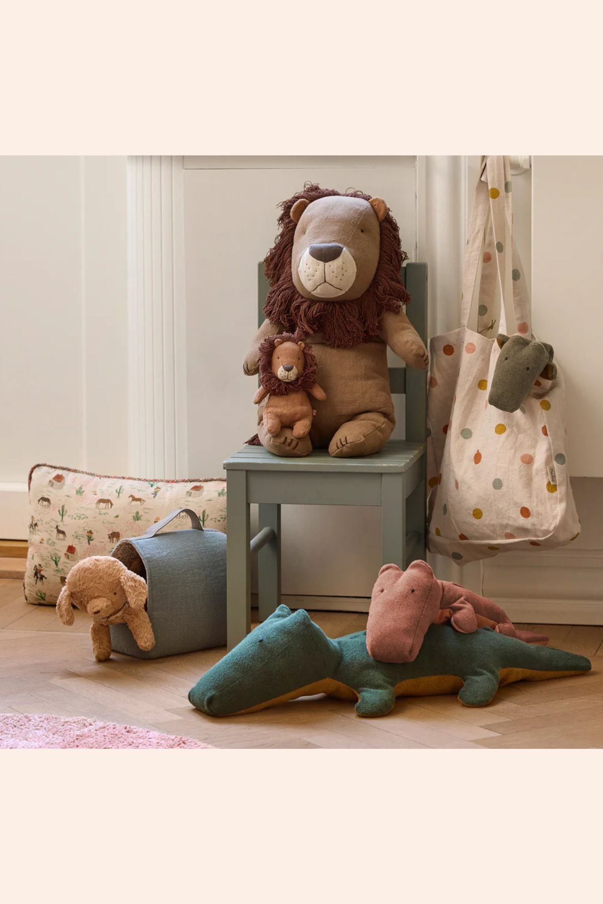 Plush toys including a lion, bear, and crocodile on a wooden floor with a neutral background.