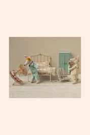 Miniature scene with toy figures in a bedroom setting on a textured beige background