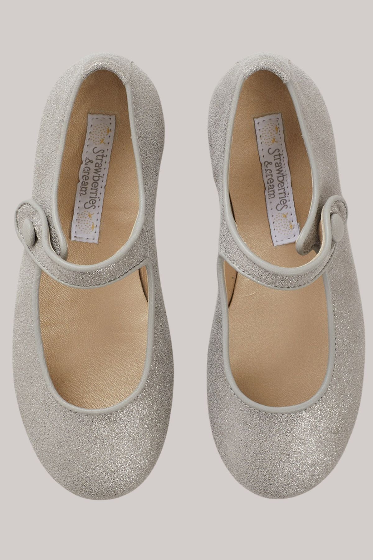 Mary Jane - Silver Leather - Strawberries & Cream - Ingrid Lewis - Designer
Pair of silver glittery shoes with a strap.